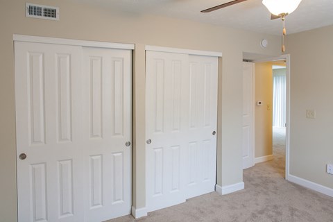 an empty bedroom with two closets and a ceiling fan