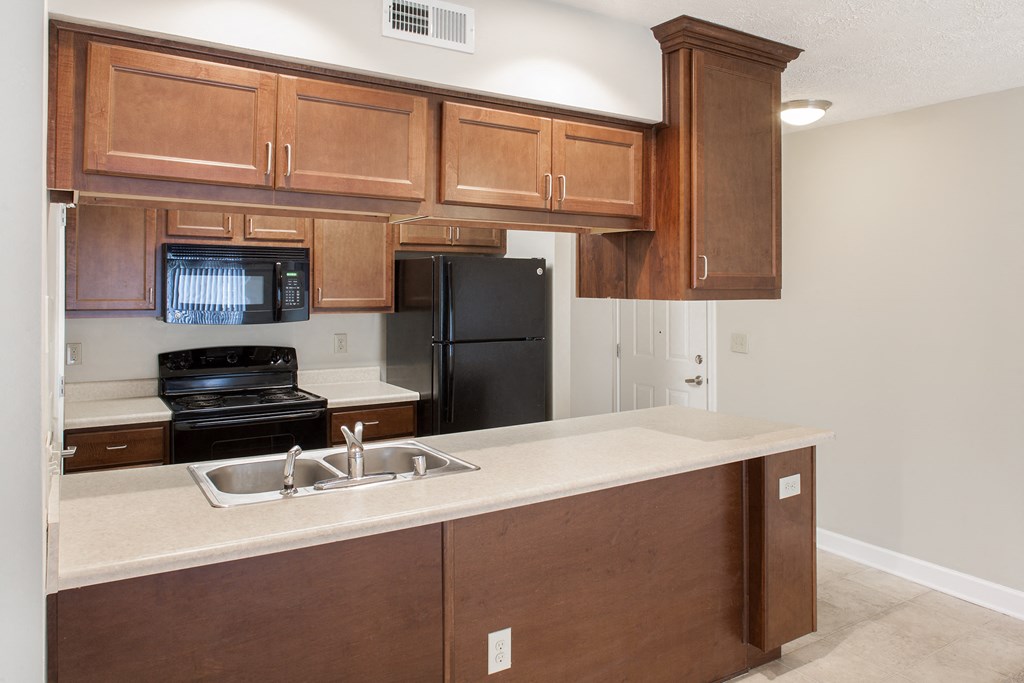 an empty kitchen with wooden cabinets and a black refrigerator