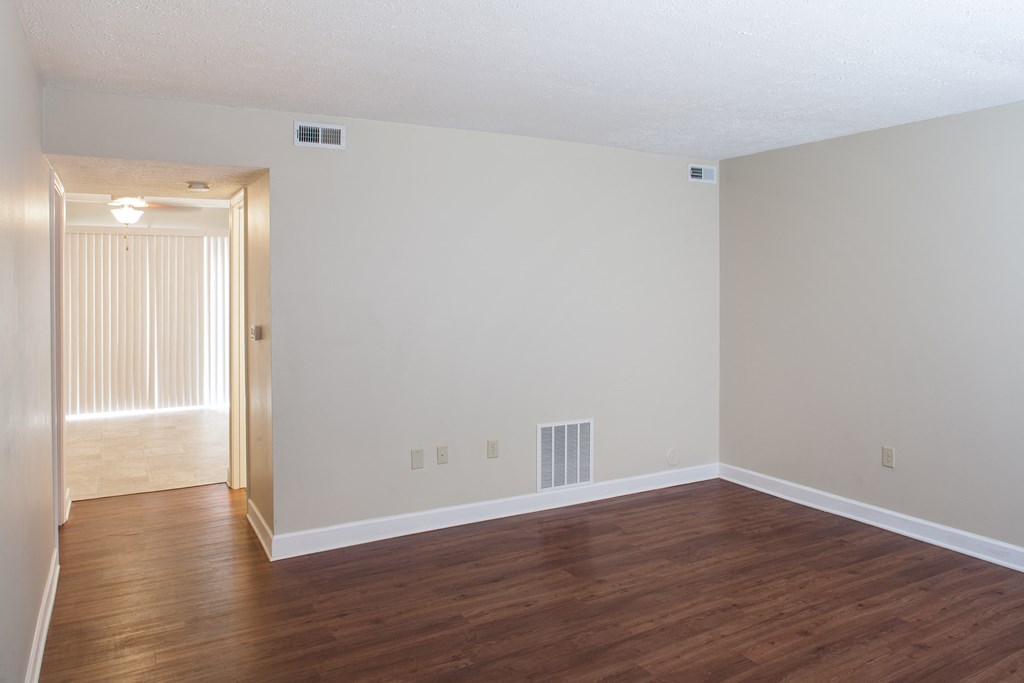 an empty living room with wood floors and white walls