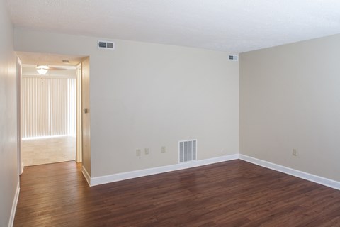 an empty living room with wood floors and white walls