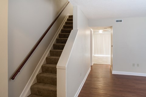 the view of the stairs from the basement of a house with white walls and wood