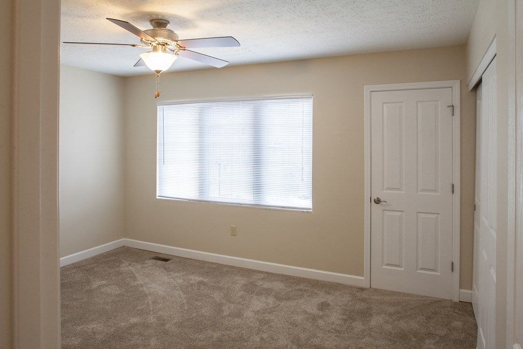 an empty bedroom with a ceiling fan and a door