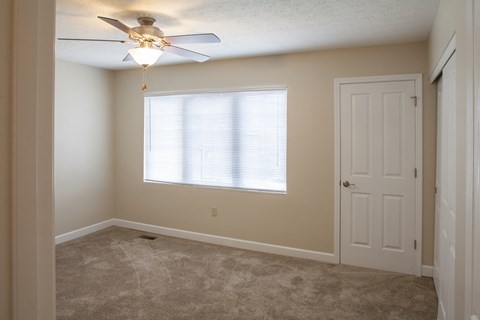 an empty bedroom with a ceiling fan and a door