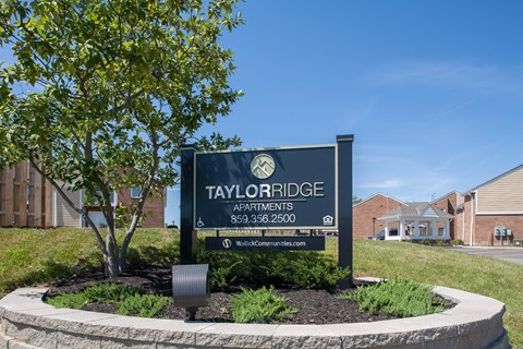 a sign apartments in front of a tree