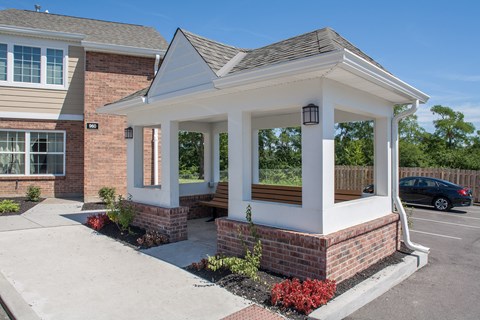 a covered porch with a bench in front of a brick house