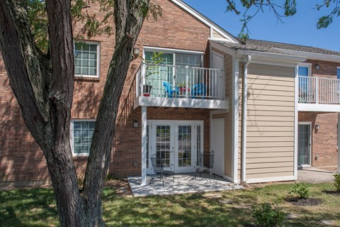 a view of the front of a brick house with a balcony and a tree