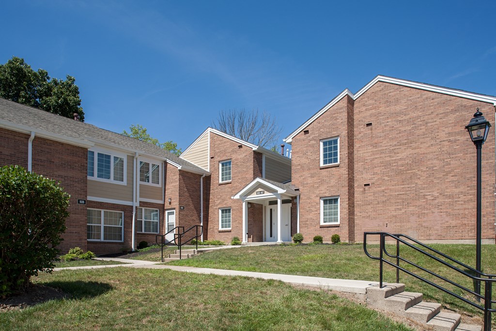 a brick apartment building with stairs and a lawn