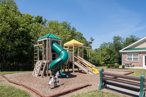a playground with a slide and playset in front of a house