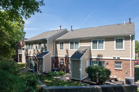 a tan house with green shutters and a yard with a tree