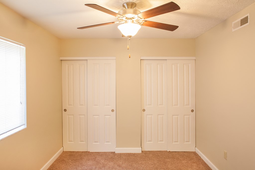 a bedroom with two closets and a ceiling fan