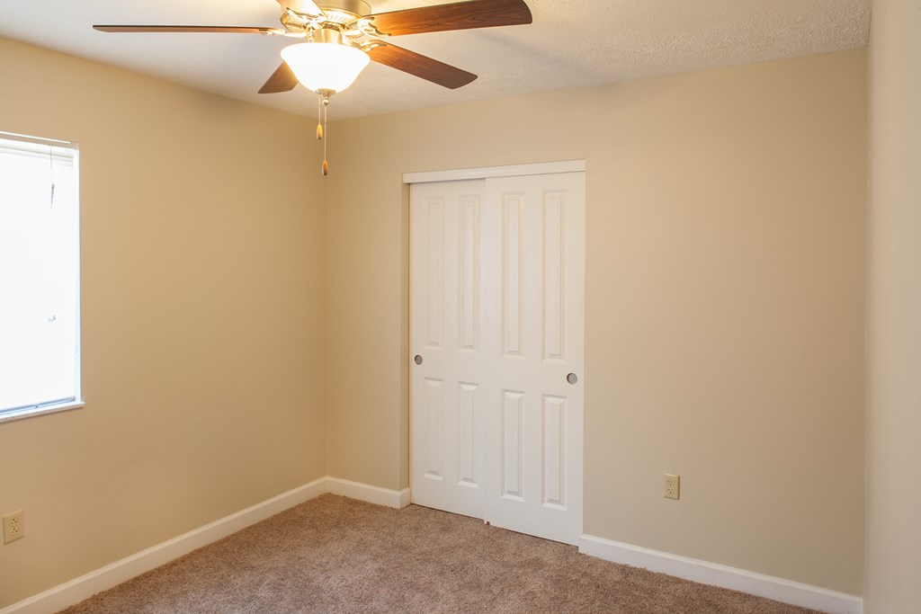 an empty bedroom with a ceiling fan and a door