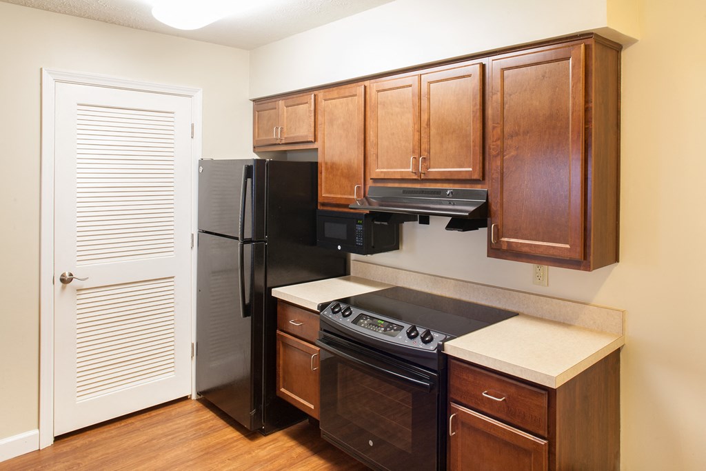 a kitchen with wooden cabinets and a black refrigerator