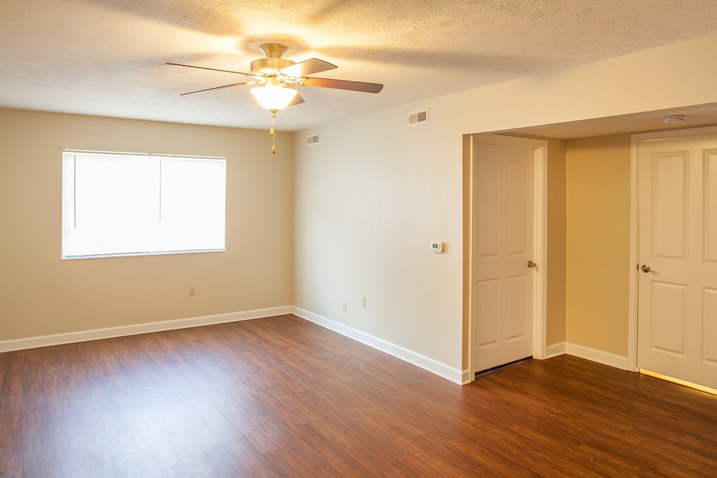 an empty living room with wood floors and a ceiling fan