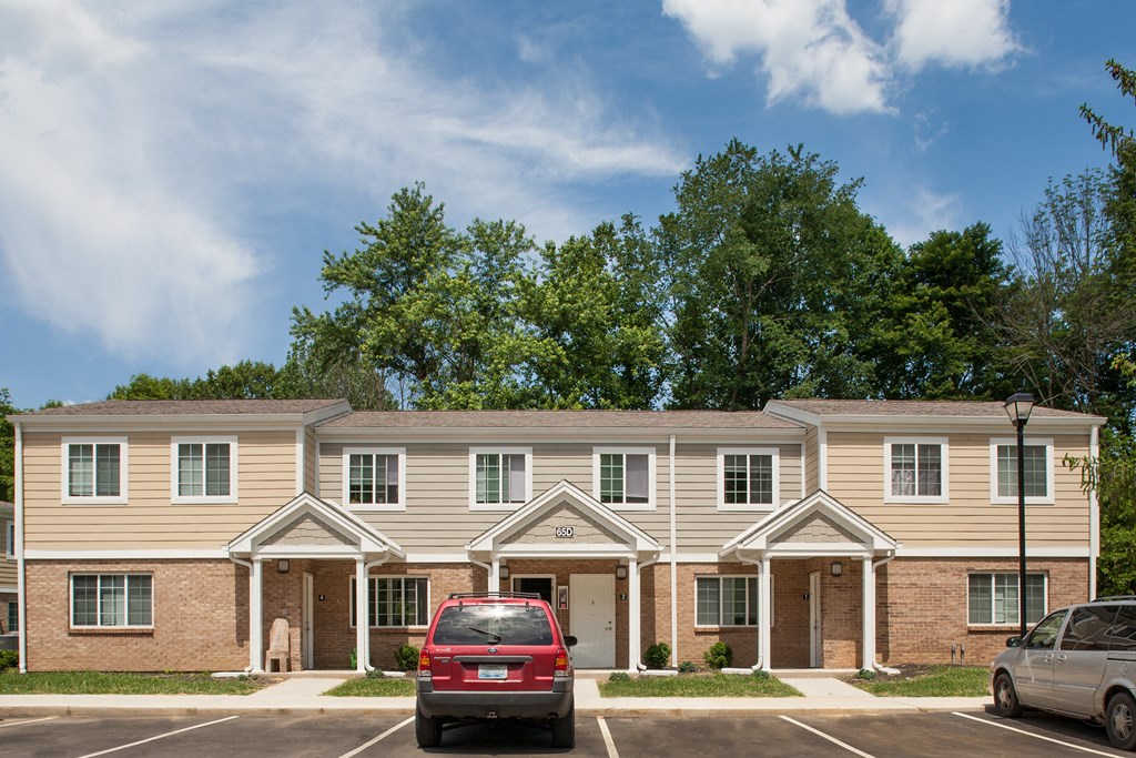 an apartment building with a red car parked in front