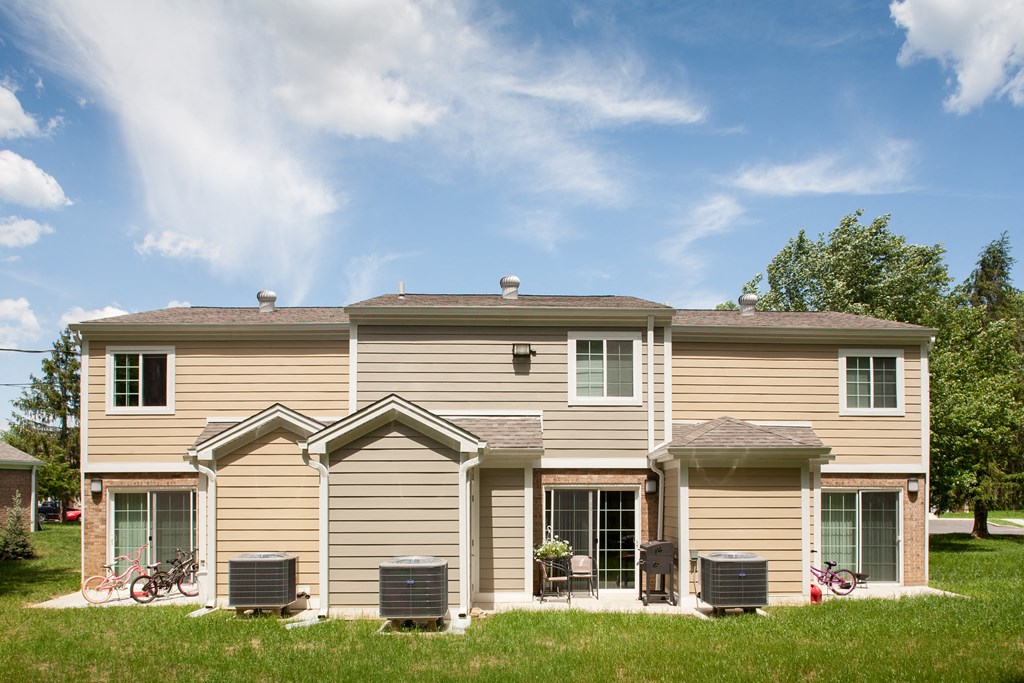 a tan house with two bikes parked in front of it