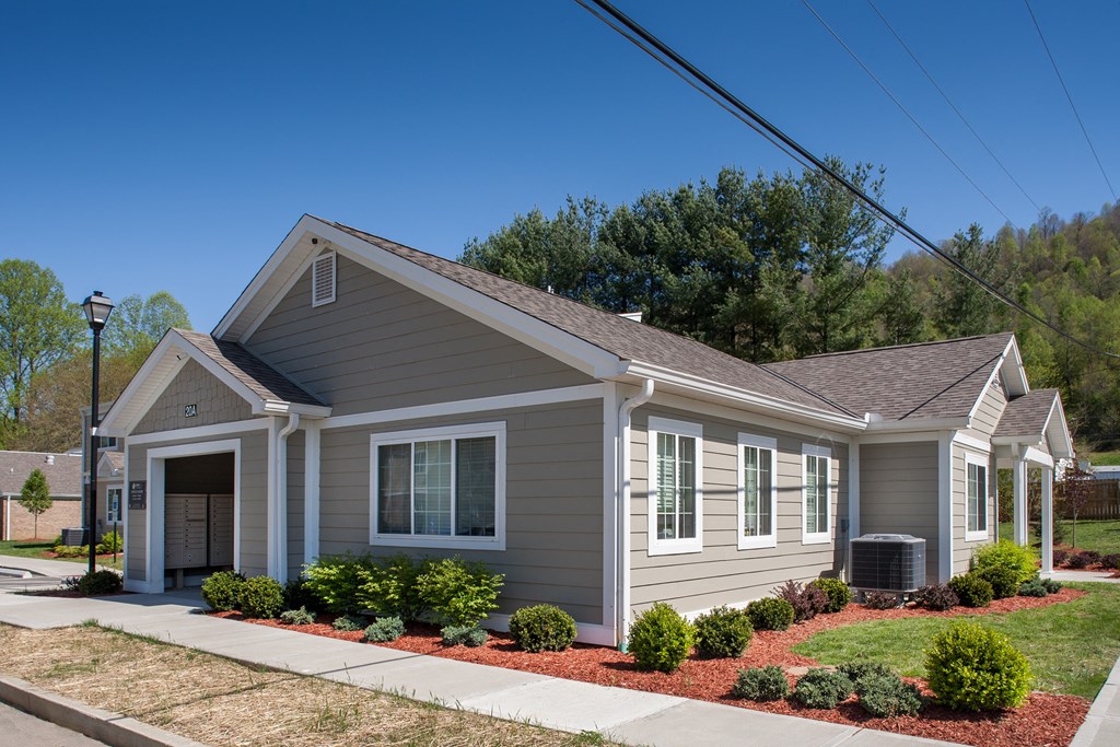 a small gray house with a sidewalk in front of it