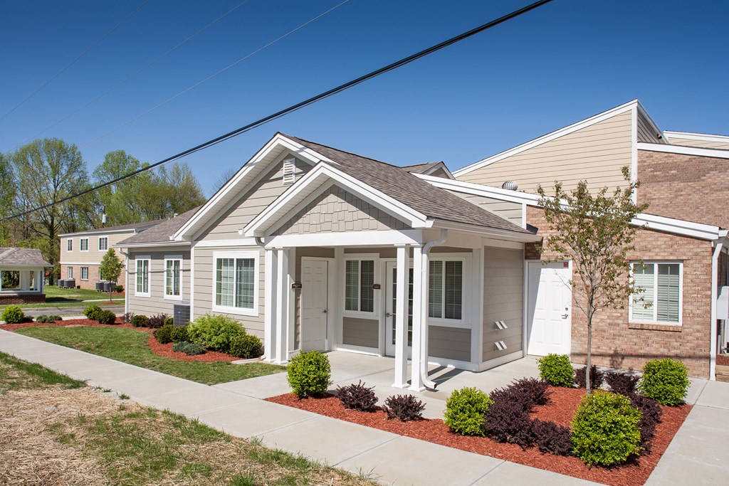 a small white house with a sidewalk in front of it