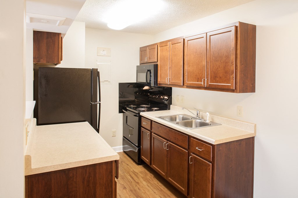 a kitchen with wooden cabinets and a black refrigerator