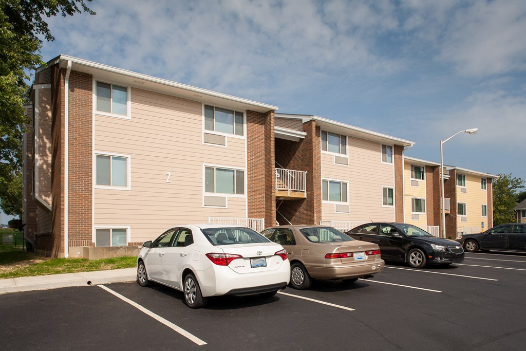 an apartment building with cars parked in a parking lot