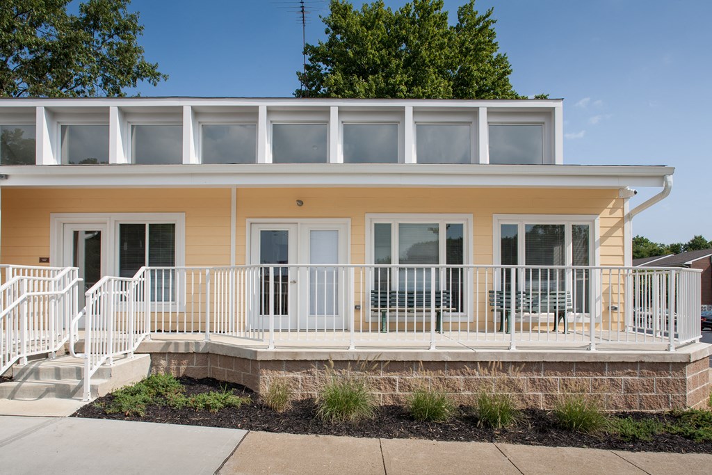 front view of a yellow house with a porch and white railings
