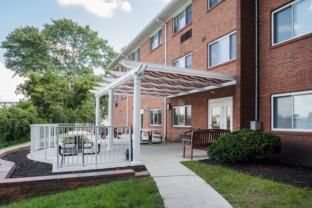 a patio with a white canopy in front of a brick building