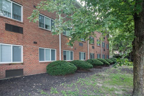 the exterior of a brick apartment building with trees and bushes