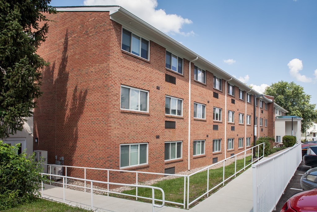 a brick apartment building with stairs and a sidewalk
