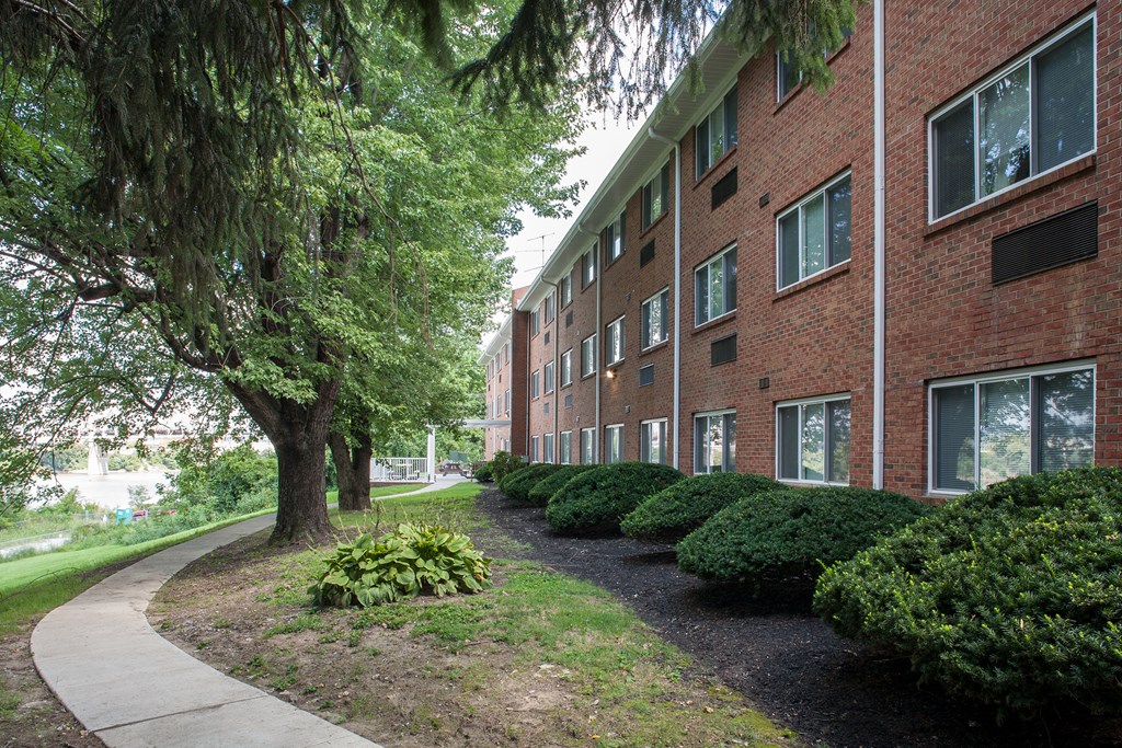 a sidewalk in front of a brick apartment building
