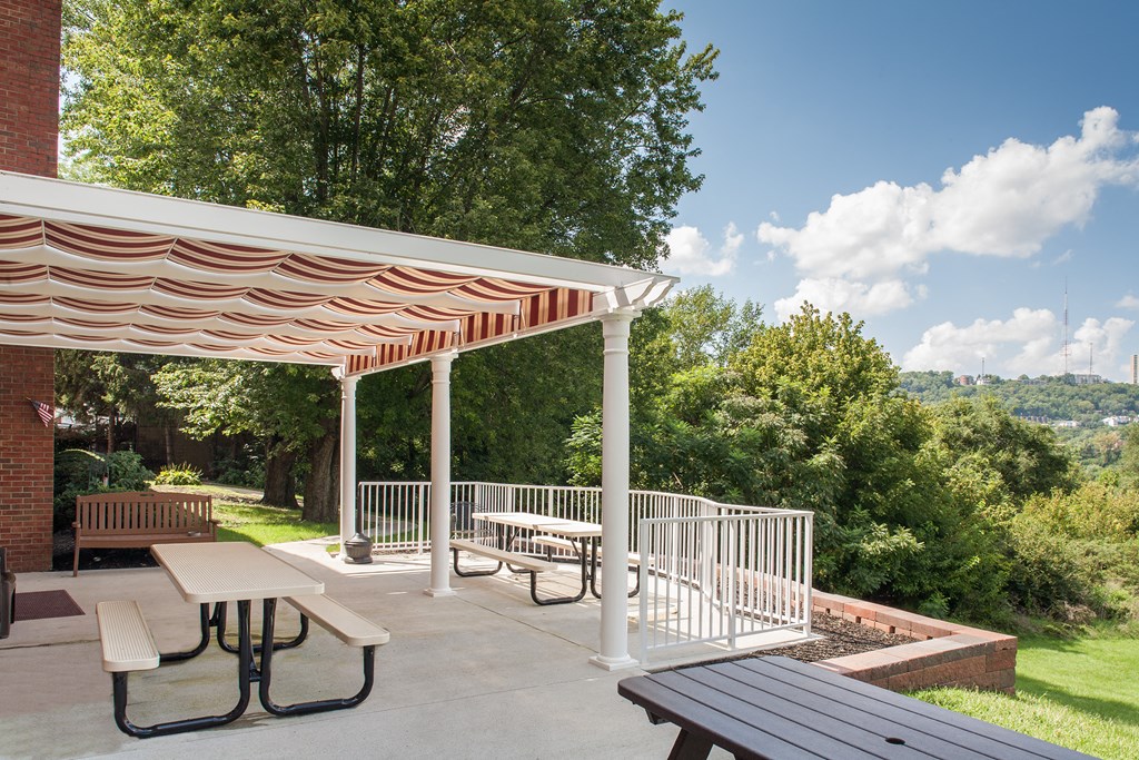a picnic area with benches and awning on a patio