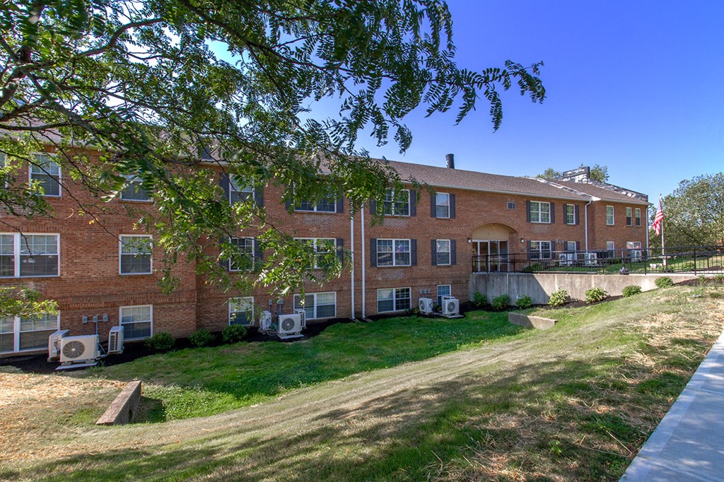 a large brick building with a yard and a hill