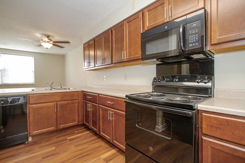 a kitchen with wooden cabinets and black appliances and a microwave