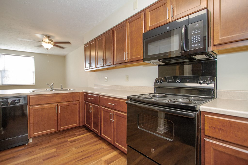 a kitchen with wooden cabinets and black appliances and a microwave
