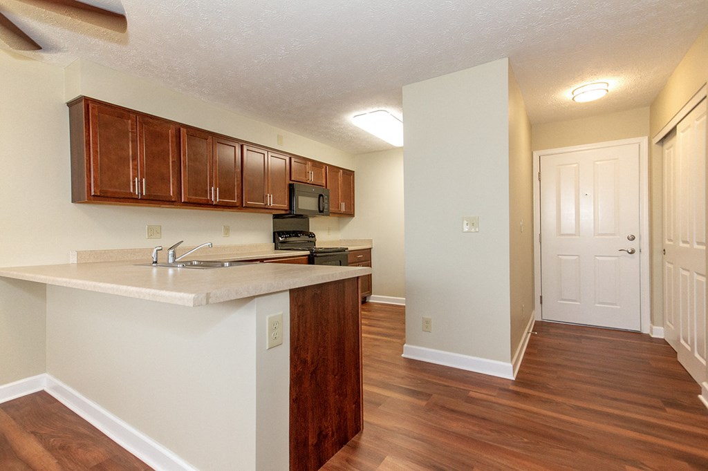 an empty kitchen with wood flooring and a white counter top