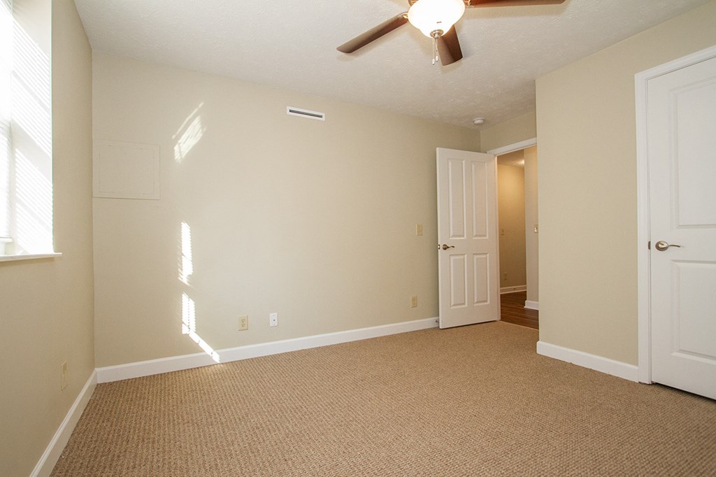 an empty living room with a ceiling fan