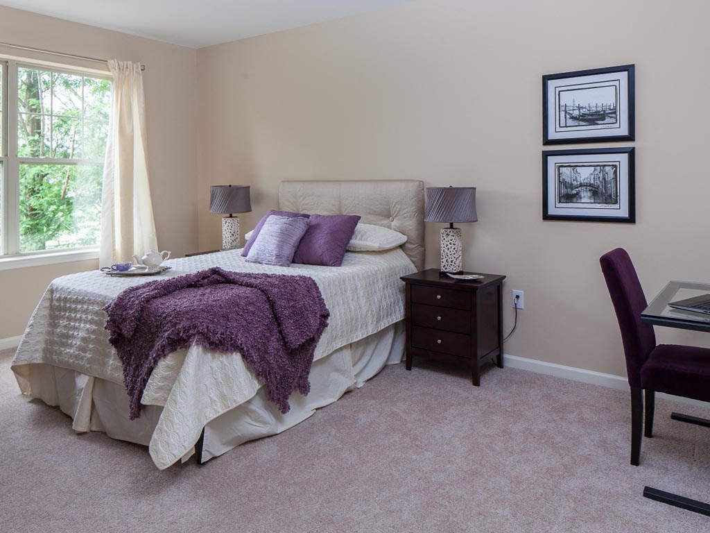 a bedroom with a bed and a desk and a window