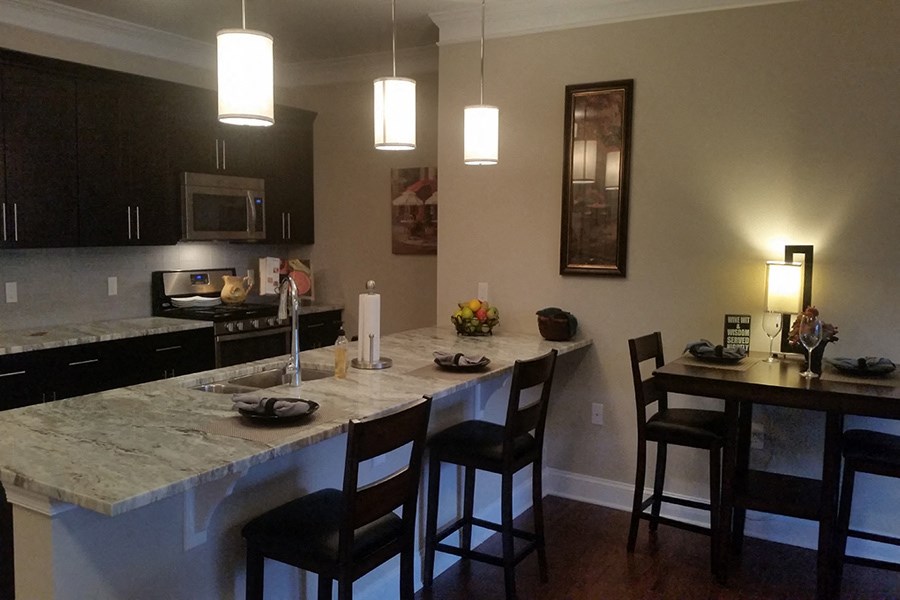 a kitchen with a marble counter top and a bar with chairs
