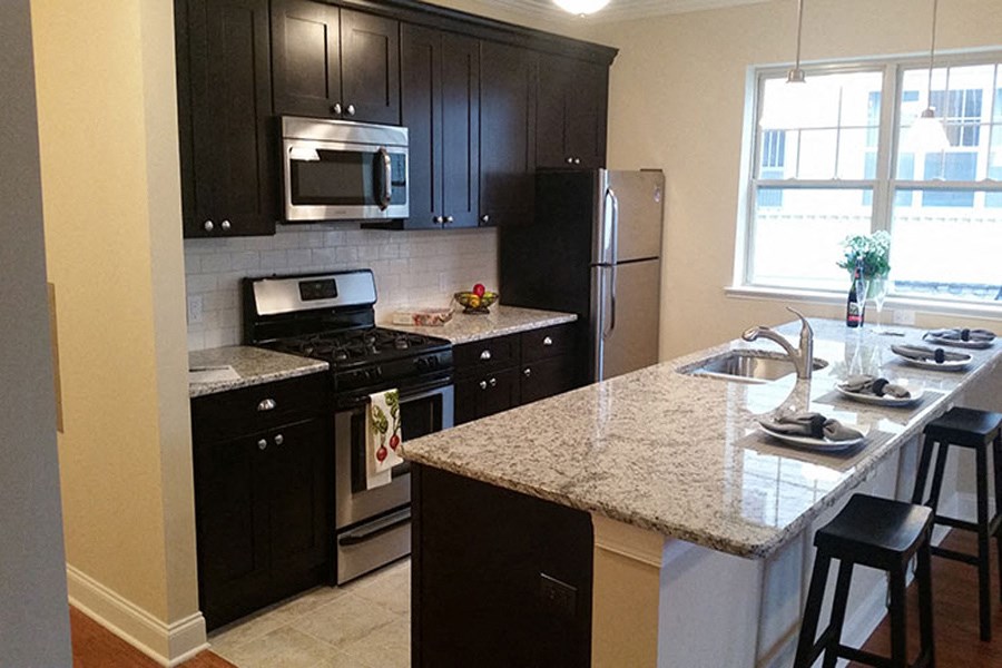 a kitchen with black cabinets and a marble counter top