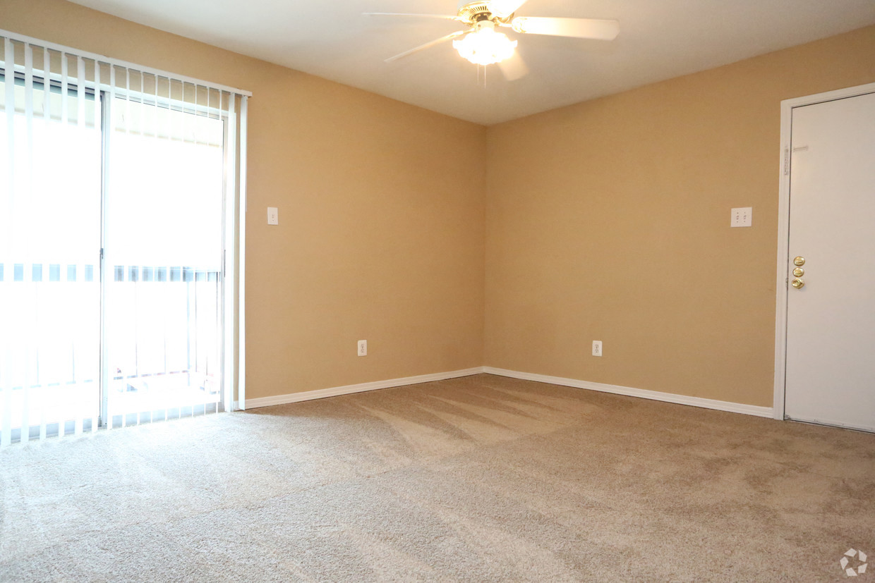 an empty living room with a large window and a ceiling fan