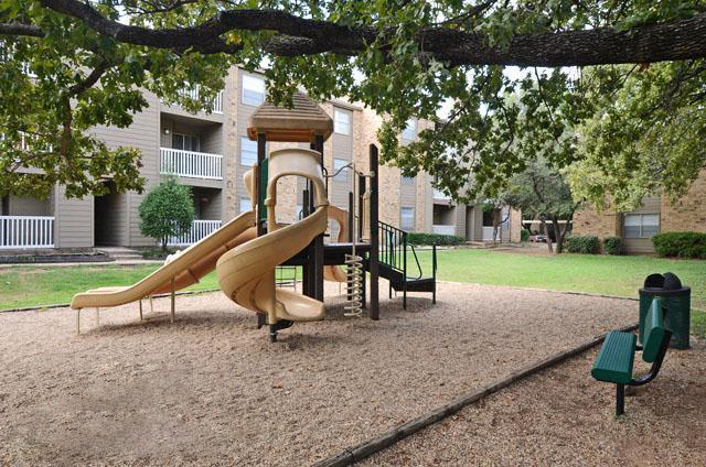 a playground with a slide and a tree