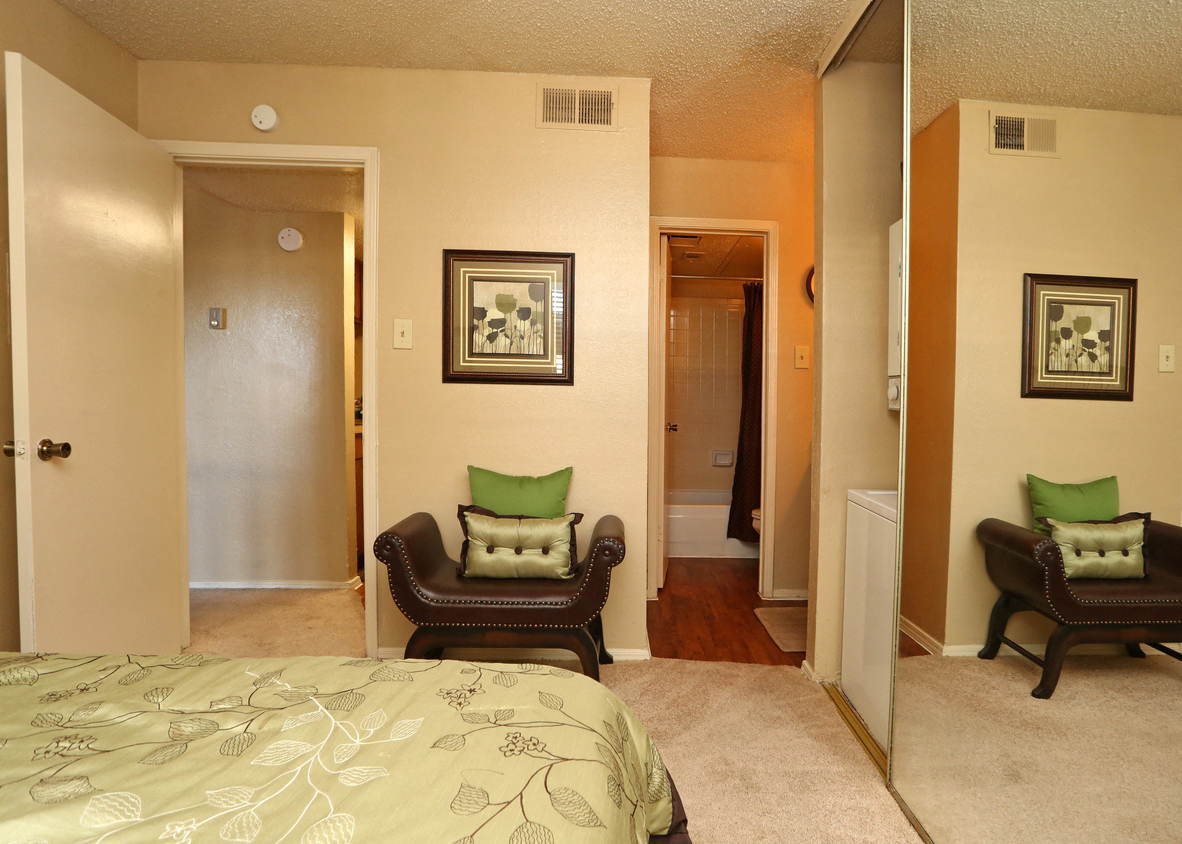 a bedroom with a bed and two chairs and a hallway