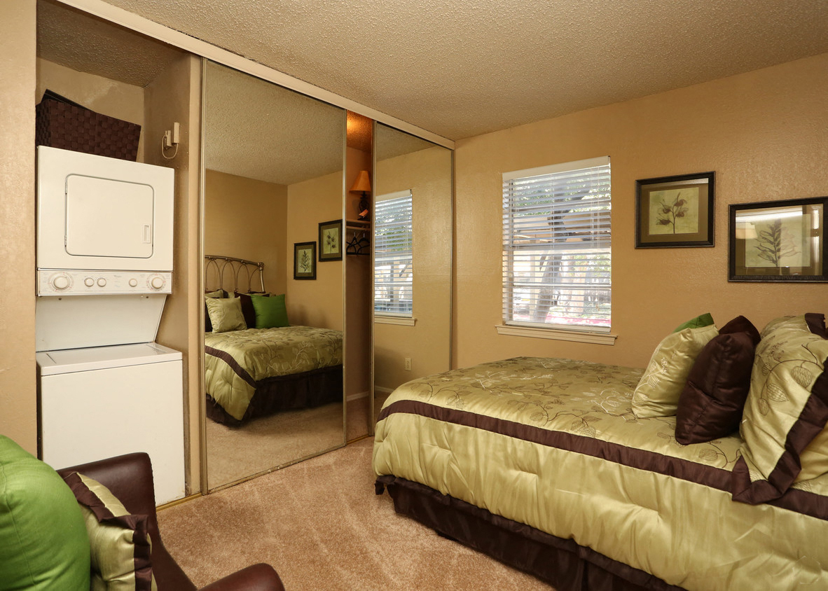 a bedroom with a bed and a refrigerator and a mirror