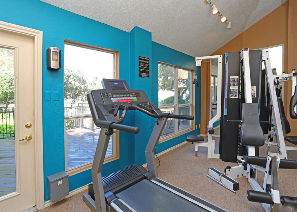 a gym with cardio equipment and a window overlooking a pool