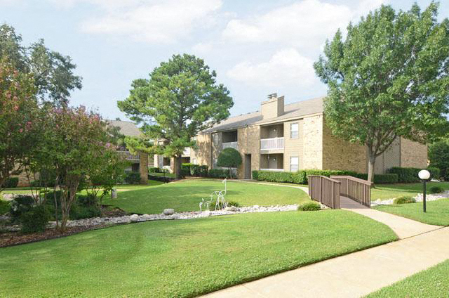 a yard with a fountain in front of an apartment building