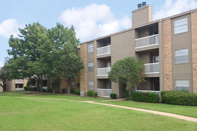 an apartment building with green grass and trees