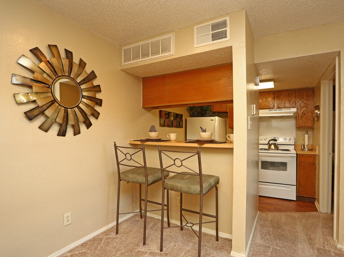 a kitchen with two stools in front of a bar with a mirror above it