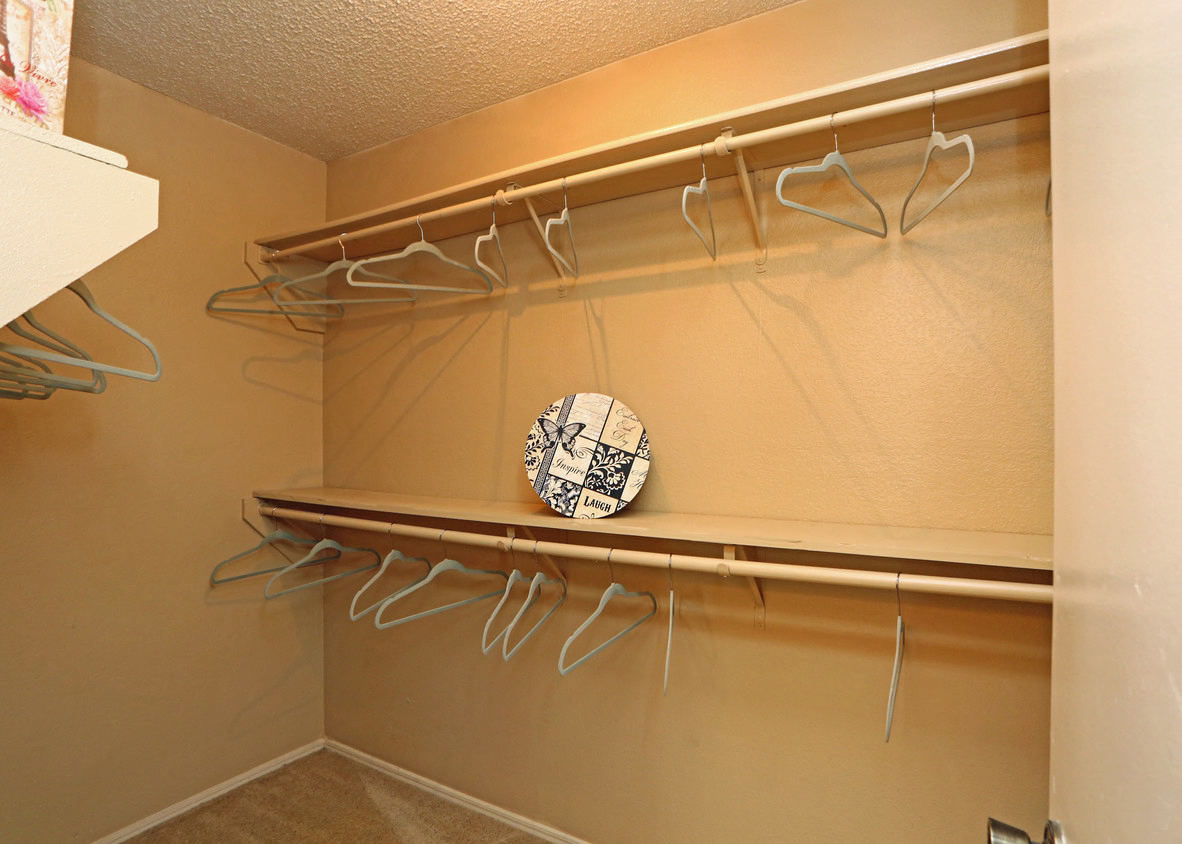 a walk in closet with hangers and a plate on a shelf