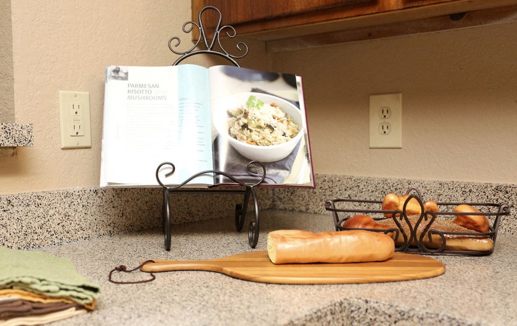 a book on a counter next to a cutting board with a bowl of food
