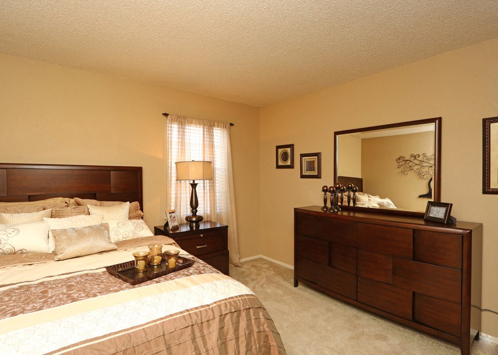 a bedroom with a bed and a dresser and a mirror
