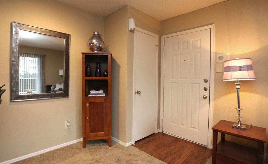 a living room with a door and a dresser and a mirror