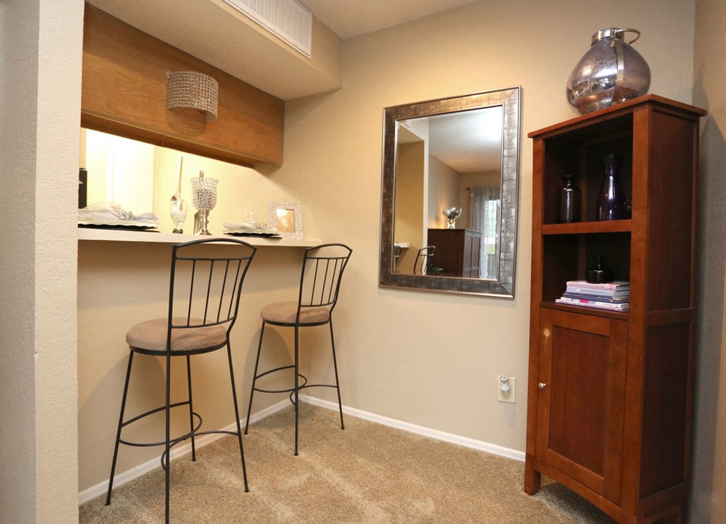 a bar with two stools in a living room with a mirror